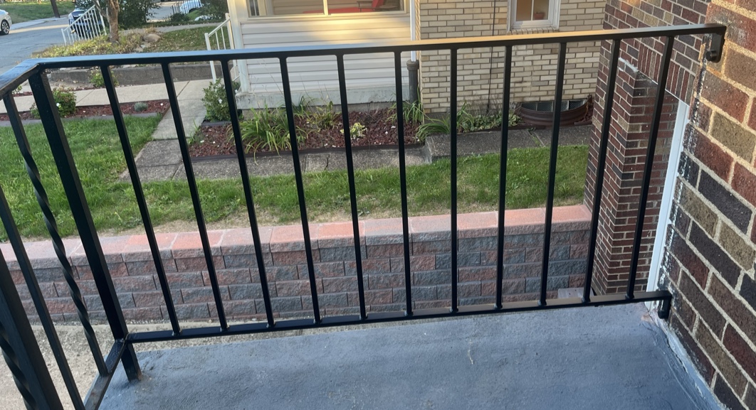 A plain black vertical-baluster iron porch railing